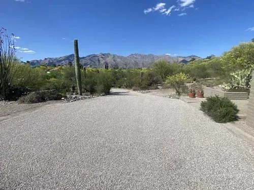 Finished chip-seal drive surrounded by desert landscaping and mountains