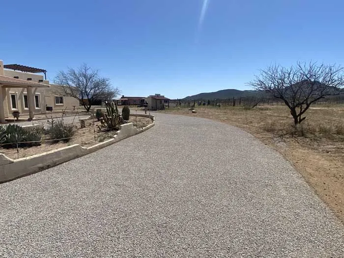 Completed chip-seal driveway curving past a desert home