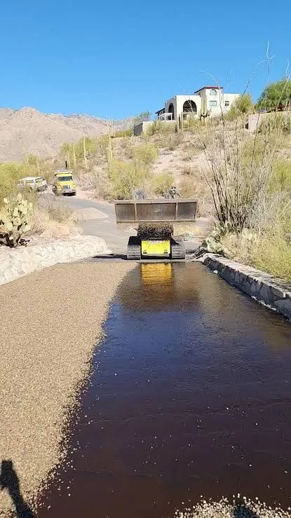 Chip-seal crew applying asphalt binder and aggregate along an Arizona driveway