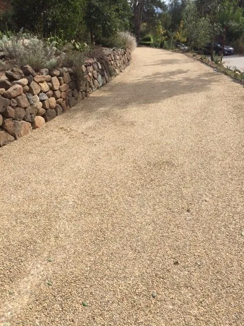 Completed chip-seal road beside a stone retaining wall